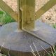 Galvanized steel transmission tower leg bolted to a concrete foundation, with a flat earthing strip running down the leg into the ground